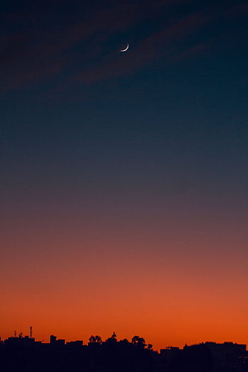 A serene crescent moon in a colorful dusk sky above a city silhouette, capturing twilight's beauty. HD phone wallpaper