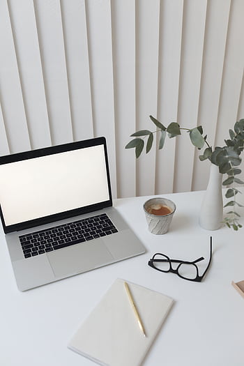 Elegant workspace featuring a blank-screen laptop, coffee, and decor for a modern office setting. HD phone wallpaper