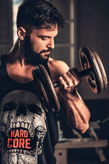 Bearded man in gym lifting a heavy dumbbell, showcasing strength and fitness. HD phone wallpaper