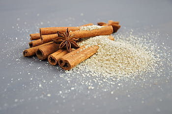 Close-up of cinnamon sticks and star anise on a sugar pile, perfect for winter recipes. HD wallpaper