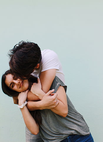 A loving couple shares a joyful embrace against a light background outdoors. HD phone wallpaper