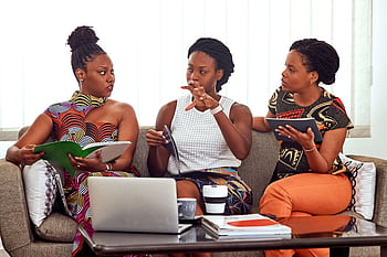 Three African American women engaged in a collaborative business meeting indoors. HD wallpaper