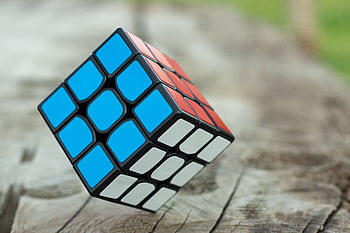 Colorful Rubik's Cube resting on a wooden surface, showcasing vibrant geometric patterns. HD wallpaper