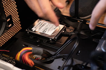 Hands installing a hard drive in a computer case, emphasizing technology and connectivity. HD wallpaper