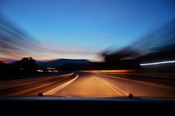 Blurred highway scene with car lights at twilight, showcasing motion and speed. HD wallpaper