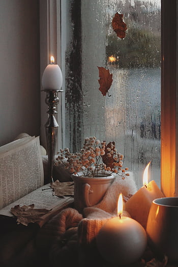 Warm and inviting autumn atmosphere by the window with candles, books, and raindrops. HD phone wallpaper