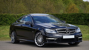 Luxurious black Mercedes Benz coupe parked on a scenic outdoor setting with lush greenery. HD wallpaper
