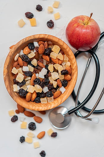 Top view of a healthy mix of nuts and dried fruits with an apple and stethoscope. HD phone wallpaper