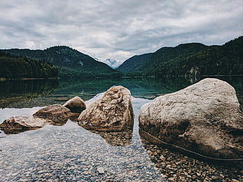Peaceful lake in Schwangau, Germany, surrounded by scenic mountains and rocks, capturing nature's serenity. HD wallpaper