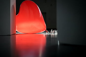 A glowing red heart-shaped balloon rests on the floor casting a warm light in an indoor setting. HD wallpaper