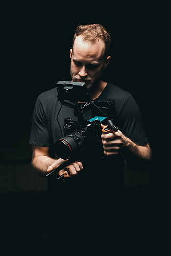 A cinematographer adjusts a camera rig with precision, ready for the next scene. HD phone wallpaper