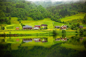 Tranquil countryside scene with houses reflected in a calm river. HD wallpaper