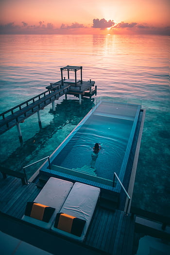 Experience ultimate relaxation at a luxury Maldives resort with an infinity pool overlooking the ocean at sunset. HD phone wallpaper
