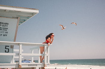 Stylish woman in red swimsuit posing at a beach lifeguard tower. HD wallpaper