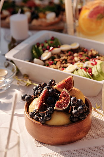 A wooden bowl filled with fresh figs and grapes, perfect for a gourmet fruit salad. HD phone wallpaper