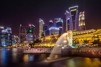 Dazzling view of the Singapore cityscape with Merlion and illuminated skyscrapers at night. HD wallpaper