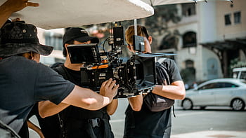 A film crew operates a RED camera on a city street, capturing a professional scene. HD wallpaper