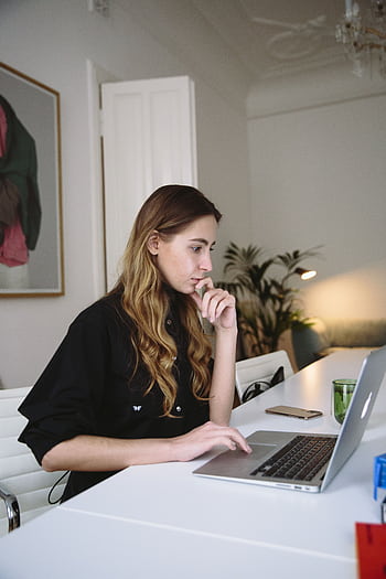 Woman deeply focused on working at a laptop in a stylish home office setting. HD phone wallpaper