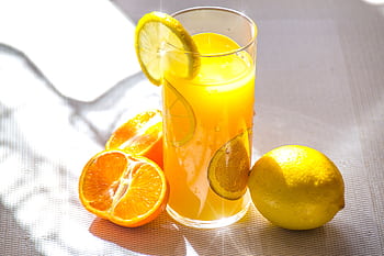 Bright and refreshing citrus juice in a glass with fresh lemon and orange slices. HD wallpaper