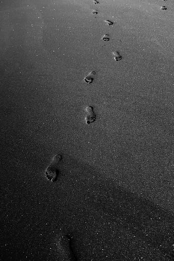 Black sand beach with footprints in monochrome, offering a minimalist and serene view. HD phone wallpaper