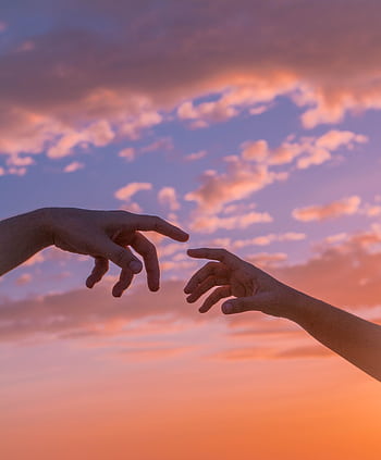 Two hands reaching towards each other against a vibrant sunset sky, symbolizing connection and unity. HD phone wallpaper