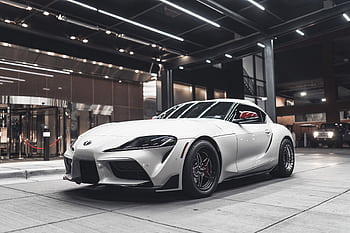 A white sports car displayed indoors, showcasing its design and luxury appeal. HD wallpaper