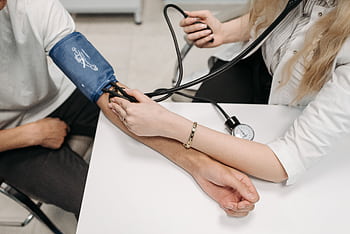 A doctor measures a patient's blood pressure with a sphygmomanometer during a consultation. HD wallpaper