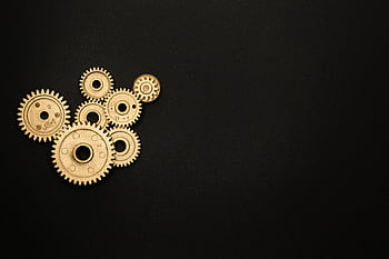 Gold gears on a black background representing industry, mechanics, and teamwork. HD wallpaper