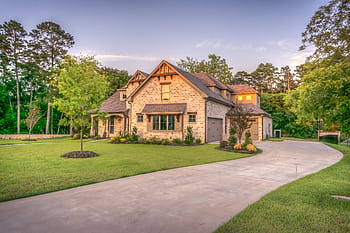 Elegant stone family home surrounded by trees, lush lawn, and vibrant garden. HD wallpaper