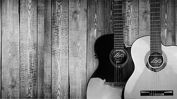 Two acoustic guitars in black and white against a textured wooden wall background. HD wallpaper