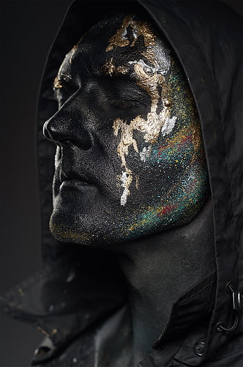 Close-up artistic portrait of an adult with black and gold face paint in a moody setting. HD phone wallpaper