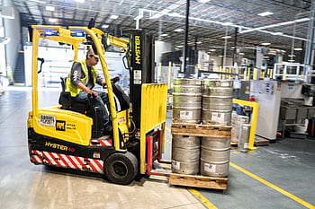 Forklift operator in warehouse moving beer kegs for distribution. HD wallpaper