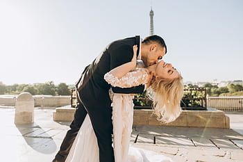 A joyful bride and groom kiss with the Eiffel Tower in the background, symbolizing love and togetherness in Paris. HD wallpaper