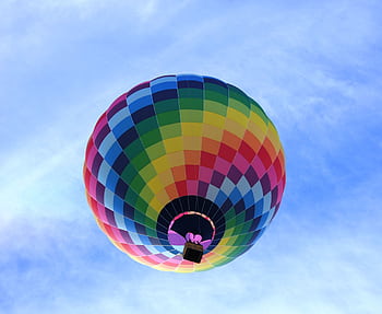 Vibrant hot air balloon soaring against a clear blue sky, showcasing a spectrum of colors. HD wallpaper