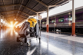 A traveler's baggage cart on an urban railway station platform at sunrise. HD wallpaper