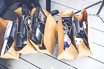 Aerial view of brown paper bags filled with various shopping goods on a wooden floor. HD wallpaper