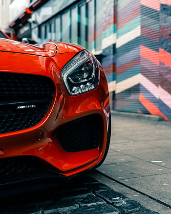Close-up of a shiny red sports car parked by a vibrant graffiti wall in Dresden, Germany. HD phone wallpaper