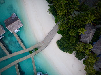 A stunning aerial view of a tropical beach resort with turquoise waters and lush greenery. HD wallpaper