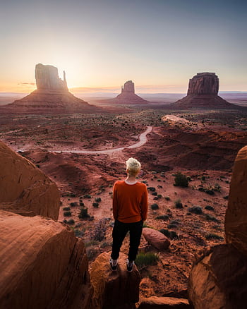 A person overlooks Monument Valley at sunrise, capturing a stunning landscape view. HD phone wallpaper