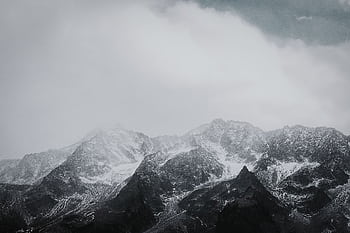 Breathtaking snowy mountain peaks under a cloudy sky, capturing winter's serene beauty. HD wallpaper