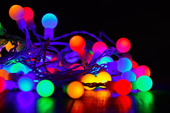Vibrant close-up of colorful glowing string lights on a dark background. HD wallpaper