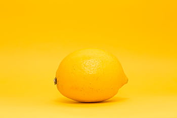 Bright lemon showcased on a uniform yellow backdrop, highlighting freshness and citrus appeal. HD wallpaper