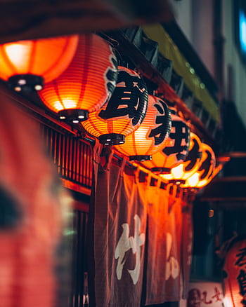 Illuminated Japanese lanterns casting a warm glow outside a restaurant in Tokyo, Japan. HD phone wallpaper