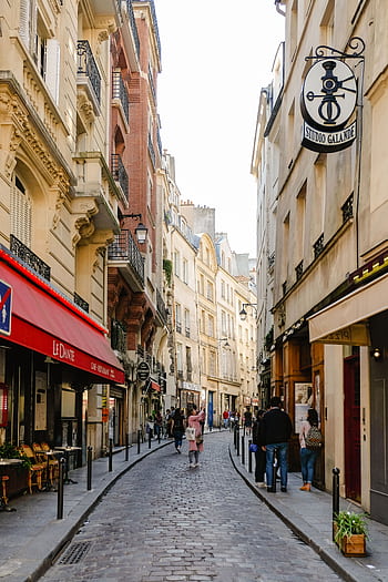Quaint Paris street lined with historic buildings and shops, capturing a vibrant urban scene. HD phone wallpaper