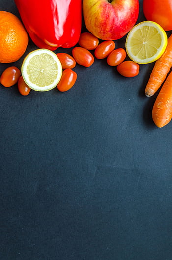 Colorful arrangement of fresh produce including citrus, carrots, and tomatoes on a dark backdrop. HD phone wallpaper