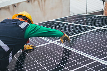 Technician installing solar panels on a rooftop for sustainable energy solutions. HD wallpaper