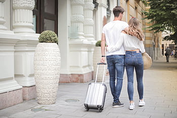 Happy young couple with luggage strolling through a city on a sunny day. HD wallpaper