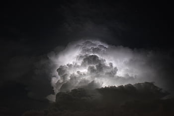 Powerful lightning illuminates dark storm clouds at night, creating a dramatic and mysterious sky. HD wallpaper