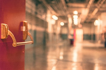 Abstract of a blurred industrial corridor with focus on a red door handle. HD wallpaper