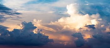 A stunning view of fluffy clouds and a colorful sky during sunset, creating a dreamy cloudscape. HD wallpaper